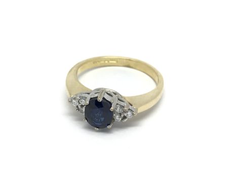 An 18carat gold ring set with a rich deep coloured central sapphire and flanked by diamonds ring size K