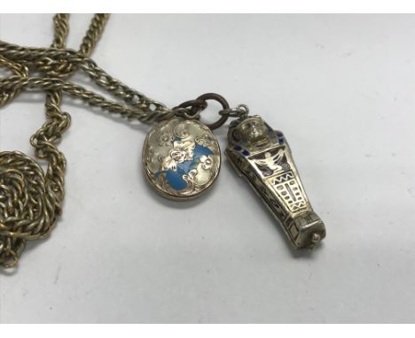 A silver and enamel pendant in the form of a mummy on a gilt metal longuard chain