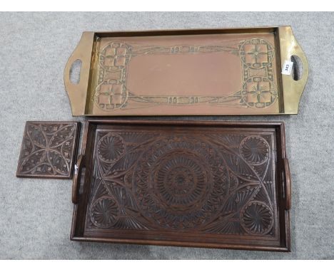 A lot comprising a brass Arts and Crafts rectangular tray, an intricately carved wooden tray, a similarly carved wooden tile 