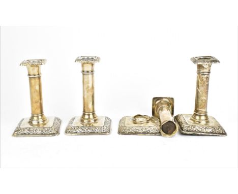 A set of four Edwardian silver candlesticks by William Hutton & Sons, Birmingham 1906, with embossed foliage to the edges of 