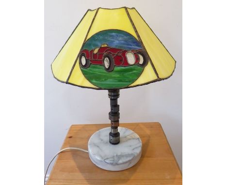 An unusual table lamp made from a racing car part; the Tiffany-style predominately yellow glass angular shade decorated with 