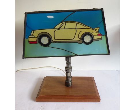 An unusual table lamp made from a racing car part and with the Tiffany-style glass shade modelled with a modern Porsche motor