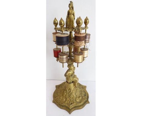 A 19th century gilt-brass bobbin stand with two tiers of cotton bobbins; the centre supported by a cherub and the figure of B