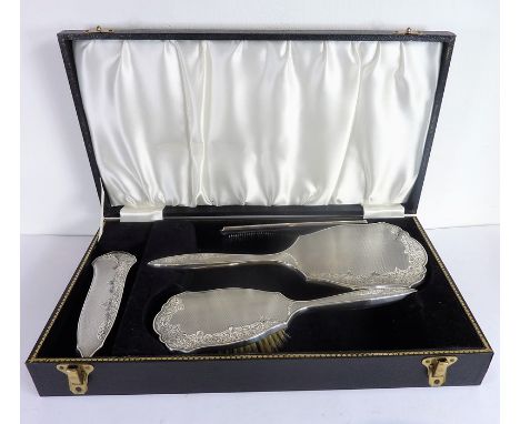 A hallmarked silver dressing table set in its case: four-piece set comprising hand-held mirror, hair and clothes brush and si