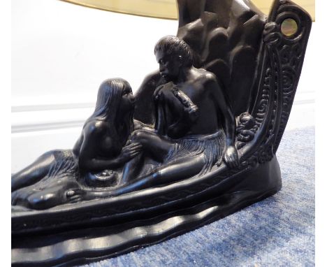 A table lamp modelled as two exotic lovers upon a canoe-style boat, together with shade