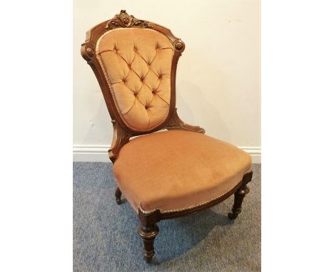 A 19th century walnut-framed and pink velour button-back upholstered nursing chair on turned tapering fluted legs terminating