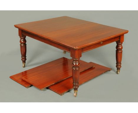 A Victorian mahogany extending dining table, with wind out action and three leaves, with rounded corners and raised on turned