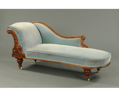 A Victorian mahogany chaise longue, with exposed moulded and foliate carved showframe, with rollover end and raised on short 