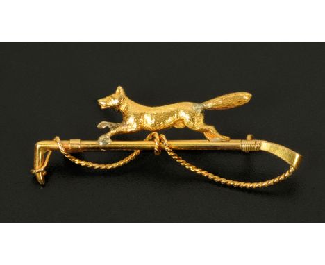 A 15 ct gold fox and riding crop hunting brooch.  Weight 3 grams.
