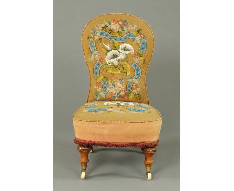 A Victorian mahogany nursing chair, with bead and woolwork tapestry cover, raised on short turned front legs terminating in c