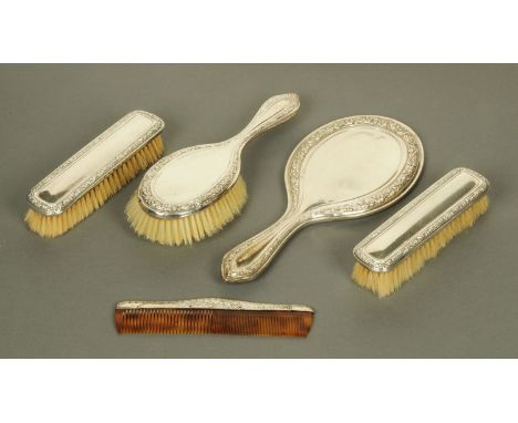 A silver backed dressing table set, mirror, three brushes and comb, Birmingham 1934.