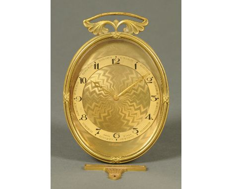 A Bucherer Swiss timepiece, in oval gilt metal frame with hanger, with engine turned face and Arabic numerals and with Swiss 