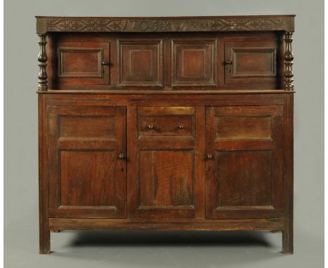 A Queen Anne oak court cupboard, dated 1705, of typical construction with series of cupboards and raised on stile feet.  Heig