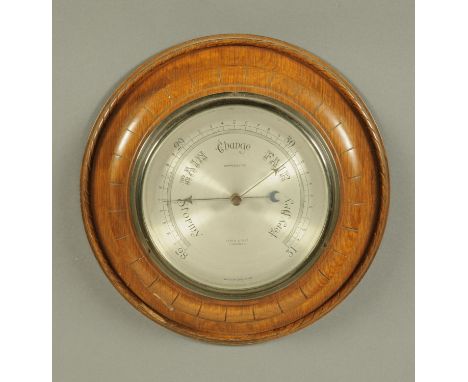 A Kendal & Dent London oak cased aneroid barometer, circa 1930.  Diameter 28 cm. 