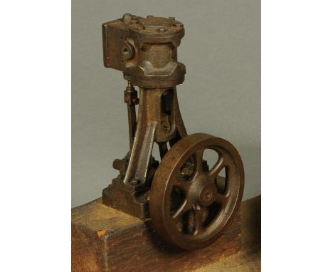 A vertical single steam engine, with two pistons, embossed "S" on head, fly wheel 7.5 cm, wooden base. 