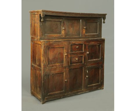 An 18th century oak court cupboard, in two sections, the top half with moulded cornice above two panelled doors, the base wit