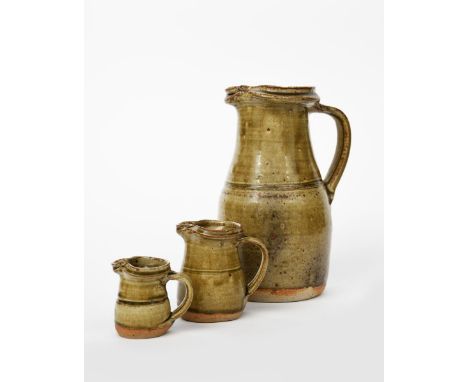 Richard Batterham (1936-2021) a tall stoneware jug, covered in an ash glaze, and two smaller graduated jugs by Richard Batter