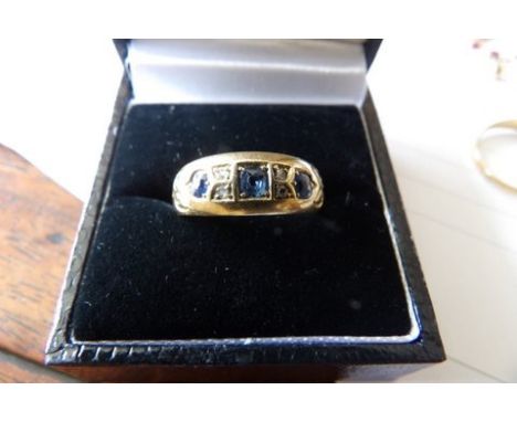 An 18ct yellow gold ring with three sapphires and diamond chips size R