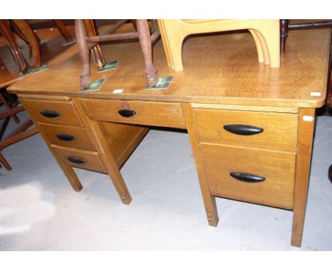 A 20th century light oak school type desk on square section supports, front central drawer above knee hole section flanked by