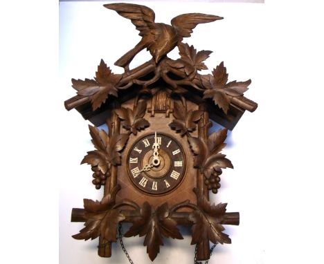 A Black Forest style cuckoo clock, dial set with Roman numerals below and flanked by carved leaf and bird decoration with con