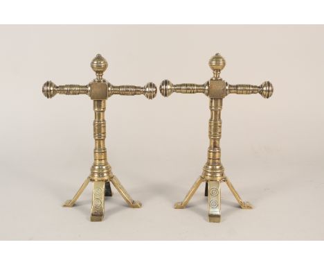 A pair of aesthetic movement brass fire dogs with turned tool rests and columns and four splayed legs, 9 1/2" high