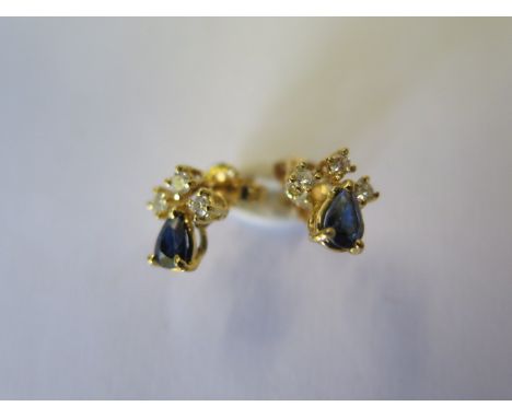 A pair of sapphire and diamond earrings - each designed as a pear shaped sapphire to the brilliant cut diamond trefoil, tests