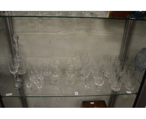 A shelf of glass drinking glasses and a decanter,