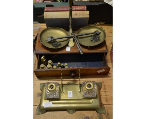 A brass inkstand, brass scales and weights with a mahogany base and three books.