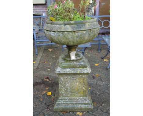 A large composite circular garden planter on an ornate pedestal base.