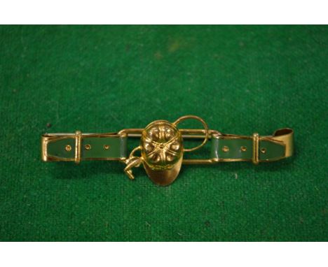 A decorative bar brooch modelled as a belt with jockey cap and whip.