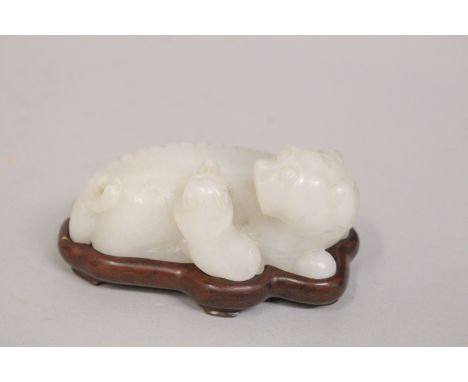A CHINESE CARVED JADE FOO DOG, with fitted wooden stand, 8cm long.