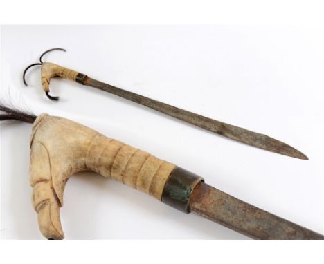 A DAYAK MANDAU OR AMBANG (KNIFE) the 53cm steel blade with a carved bone grip set with hair plumes, lacking its scabbard, ove