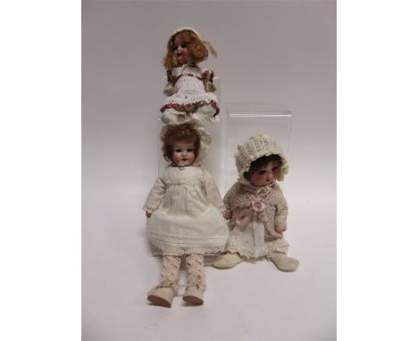 THREE BISQUE HEADED DOLLS  comprising a German bisque socket head doll, with a crimped auburn wig, sleeping grey glass eyes, 