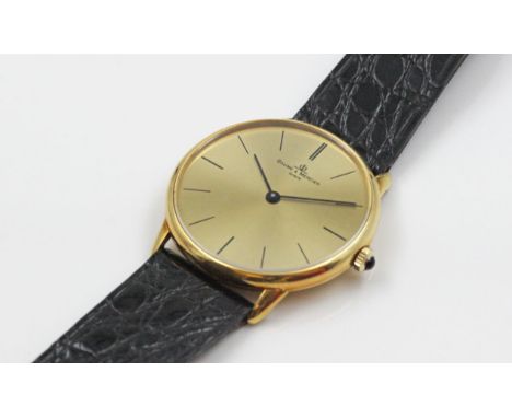 Herrenarmbanduhr "BAUME &amp; MERCIER". Rundes 750/000 GG-Gehäuse. Krone besetzt mit blauem Cabochon. Matt vergoldetes Ziffer