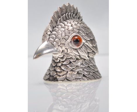 An unusual silver white metal inkwell in the form of a bird having detailed feather decoration being set with orange glass ey