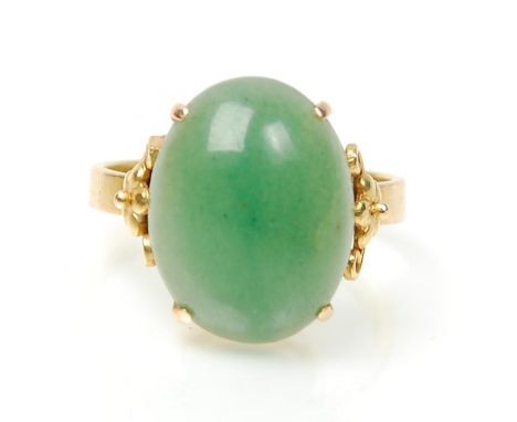 A stamped 14ct gold ring set with a round domed green jade cabochon with decorative floral design shoulders. Weight 4.8g.&nbs