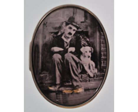 A stamped 925 silver pill box of oval form having a domed lid with a black and white enameled panel depicting Charlie Chaplin