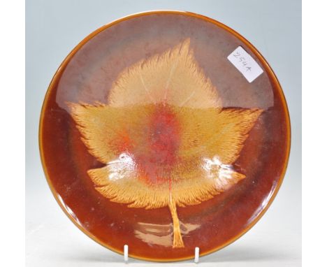 A vintage retro Poole pottery Aegean series plate of round form having&nbsp; brown glaze with a large drip glaze motif to the