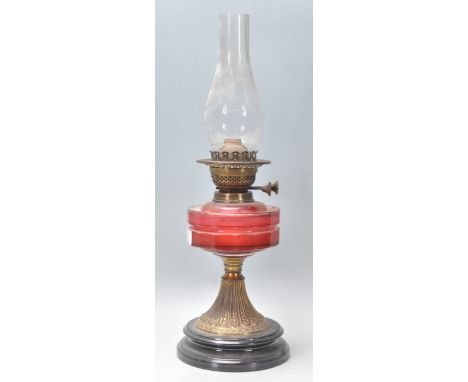 A 19th Century Victorian oil lamp having a round black lacquered plinth base with a cranberry glass reservoir complete with o