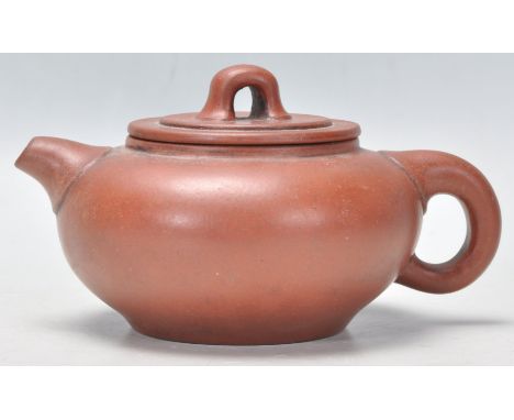 An early 20th Century Chinese Yixing red clay teapot of squat form having a short spout and finial lid having incised charact