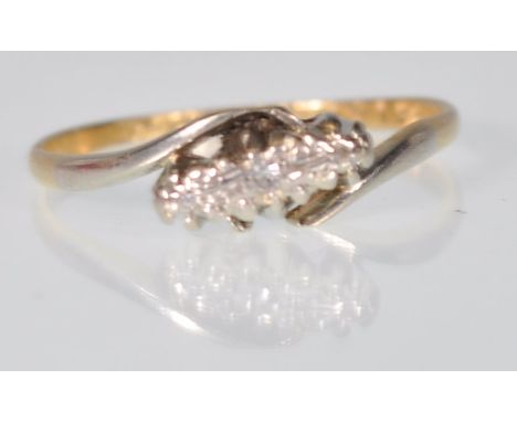 A stamped 18ct gold crossover ring set with three diamond chips set in platinum. Weight 1.7g. Size M.