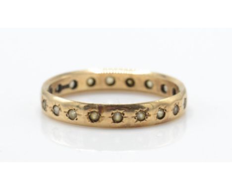 A 9ct gold full eternity ring. The ring inset with white stones to shaped band. Total weight 2.1g / Size Q.5.&nbsp;
