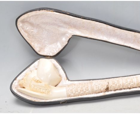 A late 19th Century Victorian long carved Meerschaum mask head pipe having a craved stem and amber mouthpiece. Within a fitte