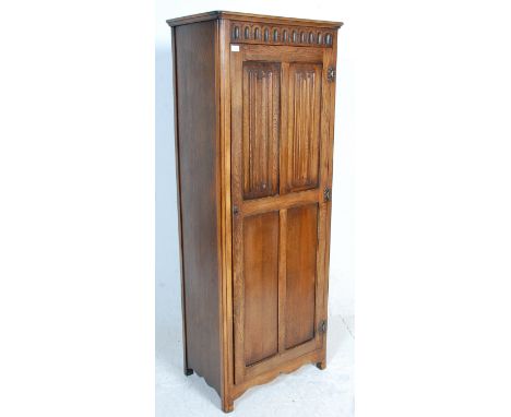 A 1930's oak Art Deco wardrobe having a singe four panelled door with carved graphic decoration to the door, with a decorativ