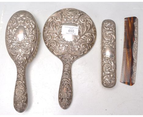An mid 20th Century silver backed dressing table set having scrolled repousse decoration consisting of hair brush, mirror, co