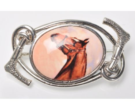A stamped silver horse riding / equestrian brooch having a central oval panel enamelled with a portrait of a horse with ridin
