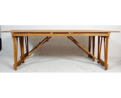 A pair of two mid 20th century vintage retro industrial folding trestle tables having wooden block legs with folding diagonal