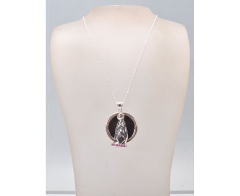 A stamped sterling silver pendant necklace having a fine link chain with a pendant in the form of a cat with a round black on