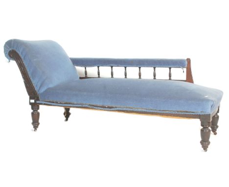 A late Victorian mahogany chaise longue daybed upholstered in blue velour fabric having spindle gallery rails and terminating