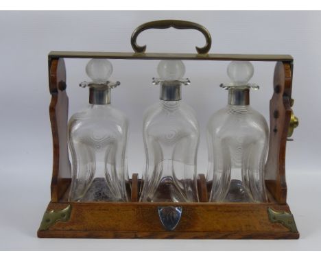 A Silver Collared Decanter Tantalus, with three ribbed shaped glass decanters and stoppers, London hallmark, dated 1897.